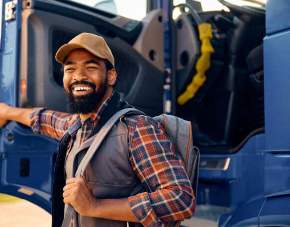 Happy African American truck driver getting in the vehicle cabin and smiling <a href=